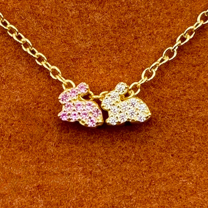 Dos conejitos de la suerte en rosa y blanco en un collar