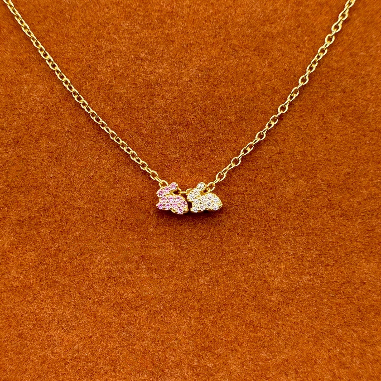 Dos conejitos de la suerte en rosa y blanco en un collar