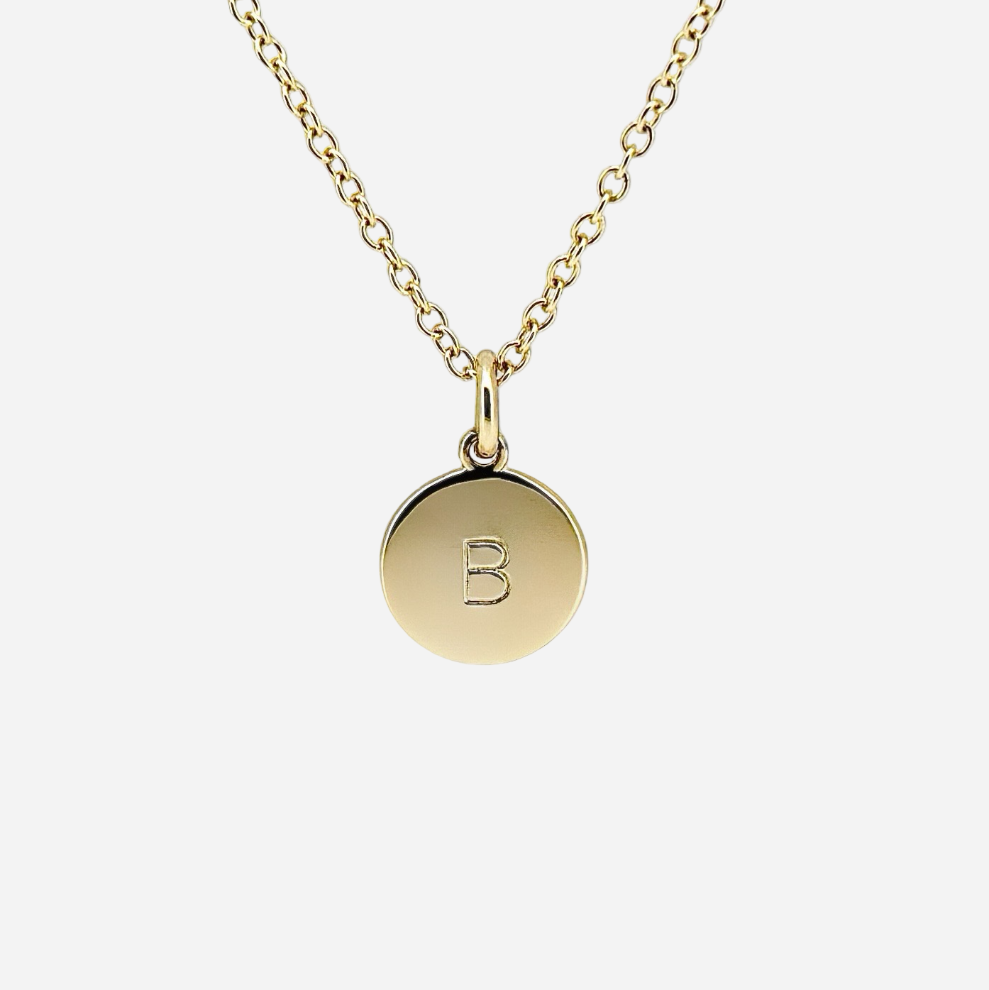 Gold necklace with a round pendant featuring the letter 'B' on a white background