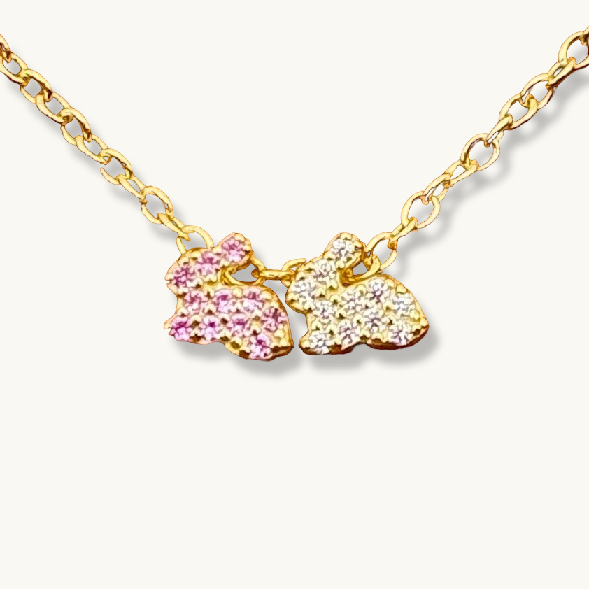 Dos conejitos de la suerte en rosa y blanco en un collar