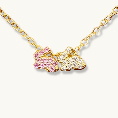 Dos conejitos de la suerte en rosa y blanco en un collar