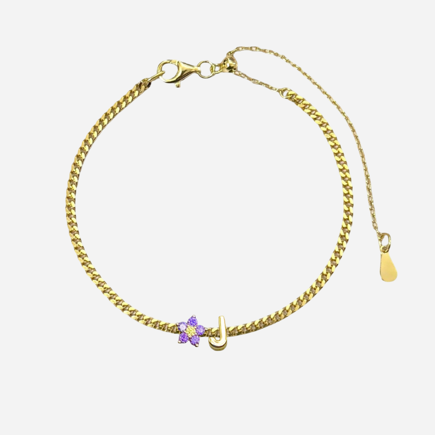 Gold bracelet with a purple flower charm on a white background